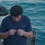 Man Tying a Hook on a Fishing Line