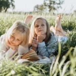 Little Girls Lying on Green Grass Field