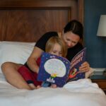 girl in red shirt lying on bed reading book