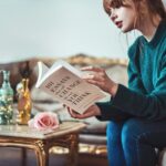 woman sitting down near table reading 101 Essays book