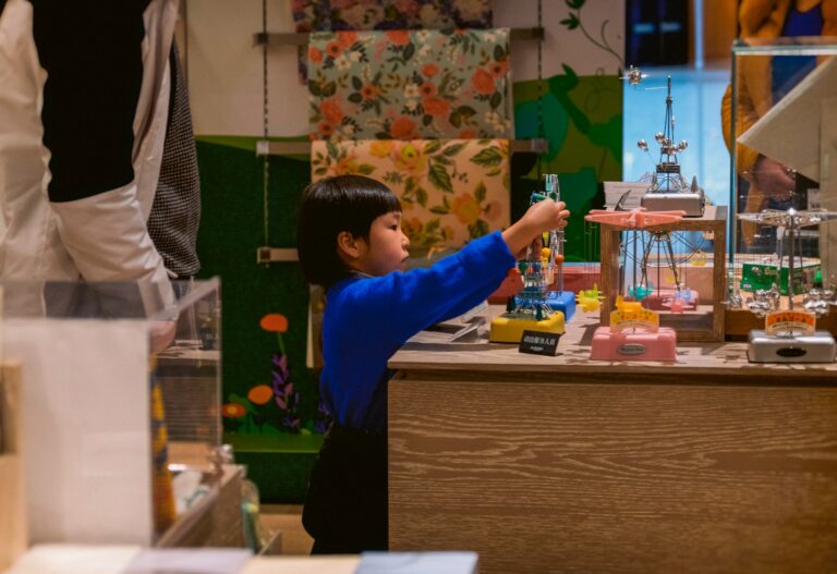 boy in blue long sleeve shirt standing beside brown wooden table